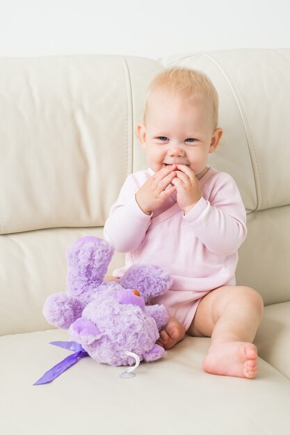 Kinder-, Säuglings- und Kindheitskonzept - Schönes niedliches weiches Baby, das auf Sofa sitzt