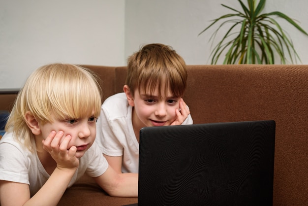 Kinder schauen auf den Laptop-Bildschirm und ruhen sein Gesicht mit der Hand aus. Freunde Teenager, die Film schauen