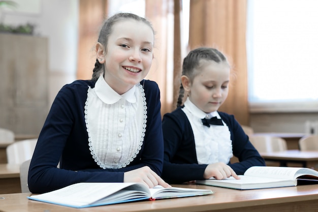 Kinder schreiben beim Sitzen an der Schulbank.