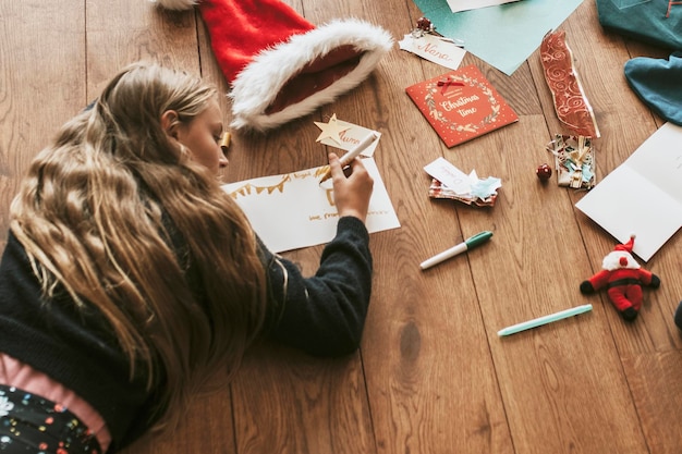 Kinder schreiben Weihnachtskarten auf Holzboden