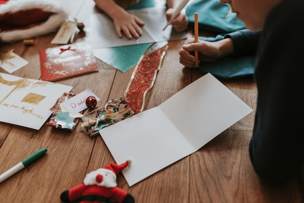 Kinder schreiben Weihnachtskarten auf Holzboden