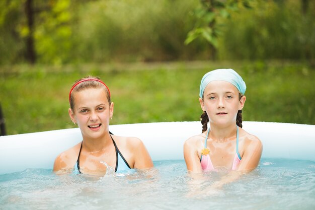 Kinder schwimmen im blauen Pool und spielen mit Wasser