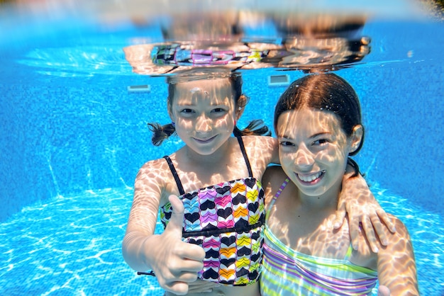 Kinder schwimmen im Pool unter Wasser, glückliche aktive Mädchen haben Spaß unter Wasser, Kindersport im Familienurlaub