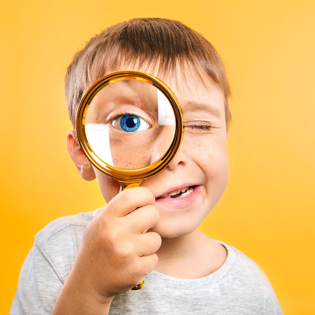 Kinder sehen durch die Lupe auf den gelben Oberflächen. Großes Kinderauge