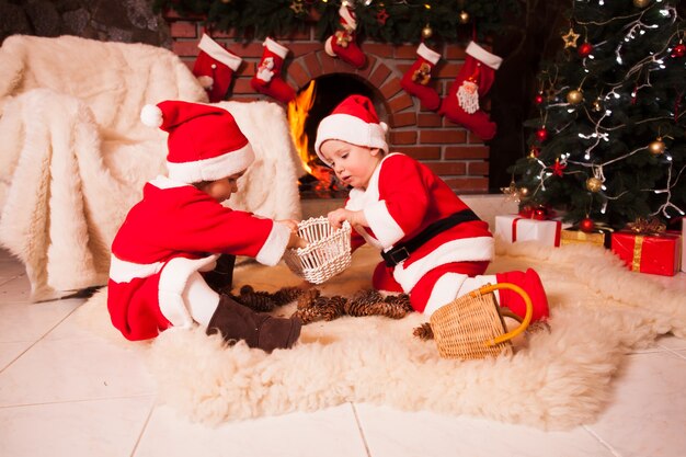 Kinder sitzen am Kamin und spielen mit Zapfen - Weihnachtsschmuck