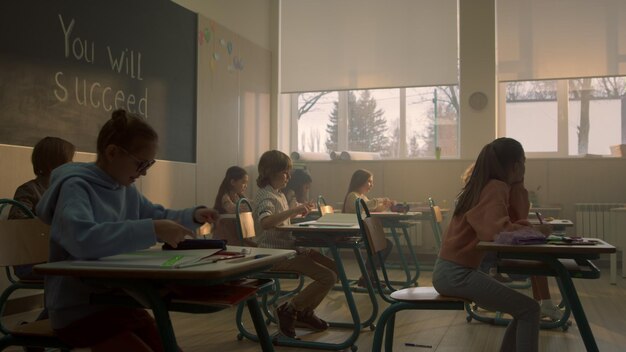 Kinder sitzen am Schreibtisch im Klassenzimmer, Studenten bereiten sich auf den Unterricht vor