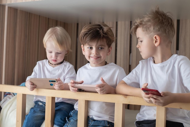 Kinder sitzen auf dem Bett, telefonieren, ignorieren sich gegenseitig, Internetspiele und virtuelle Kommunikation