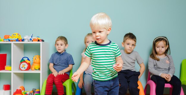 Kinder sitzen auf den bunten Stühlen im Kindergarten