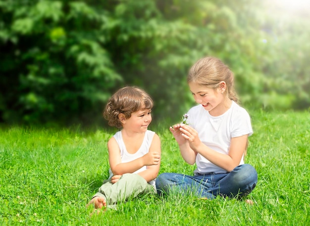 kinder sitzen draußen auf dem rasen und lächeln