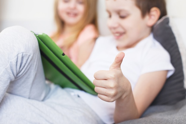 Kinder sitzen mit Tablet auf dem Bett im Zimmer