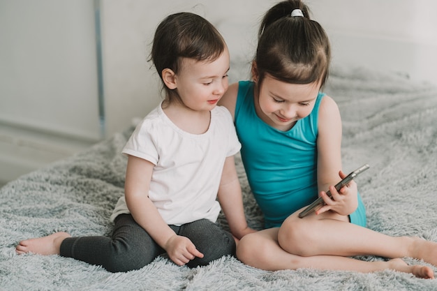 Kinder sitzen und schauen sich die Sucht der Telefonkinder nach Geräten an, die online für Kinder im Vorschulalter lernen