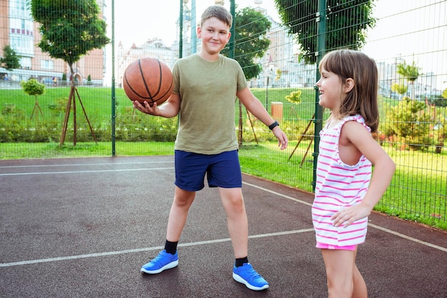 Kinder spielen Basketball auf einem städtischen Spielplatz Streetball-Basketballspiel mit zwei Spielern im Freien