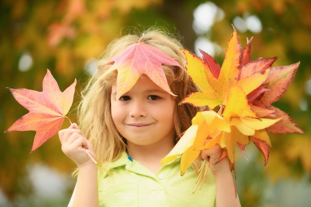 Kinder spielen im Herbstpark Kinder werfen gelbe Blätter Kind Junge mit Eichen- und Ahornblatt im Freien f
