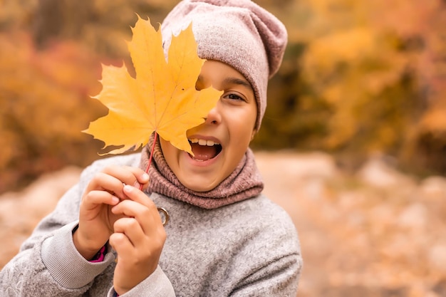 Kinder spielen im Herbstpark. Kinder werfen gelbe Blätter. Kindermädchen mit Ahornblatt. Herbstlaub. Familienspaß im Herbst. Kleinkind oder Vorschulkind im Herbst