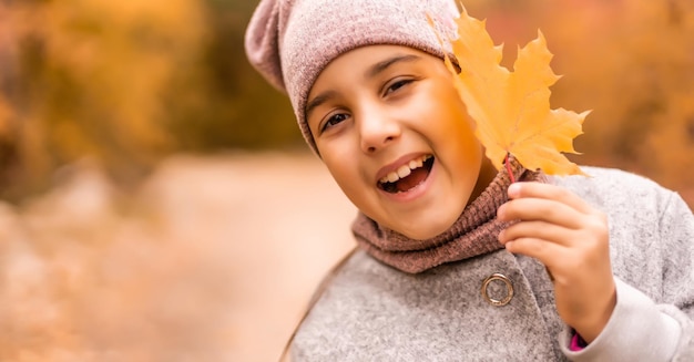 Kinder spielen im Herbstpark. Kinder werfen gelbe Blätter. Kindermädchen mit Ahornblatt. Herbstlaub. Familienspaß im Herbst. Kleinkind oder Vorschulkind im Herbst