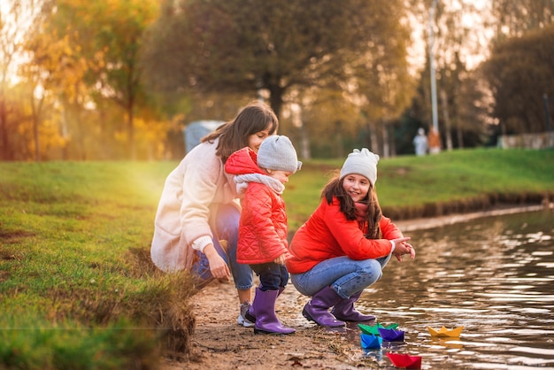 Kinder spielen mit Booten am Flussufer. sonniger Herbst. gelber Park. blauer Fluss bei Sonnenuntergang