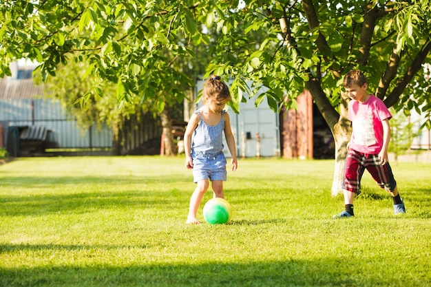Kinder spielen mit buntem Ball im ländlichen Hinterhof
