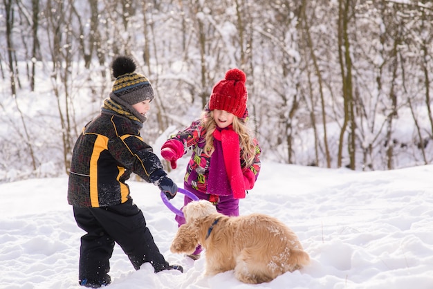 Kinder spielen mit Hund im Winterwald