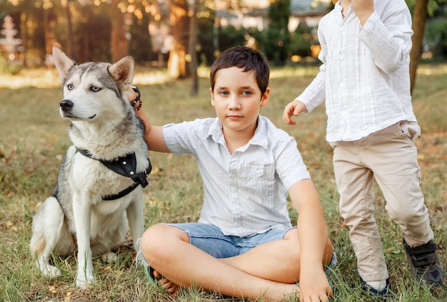 Kinder spielen mit seinem Welpen. Junge fröhliche Kinder, die am Park ruhen