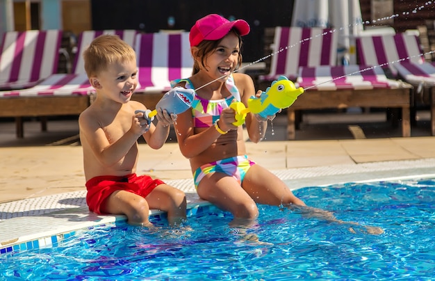 Kinder spielen mit Wasserpistolen im Pool. Selektiver Fokus. Wasser.
