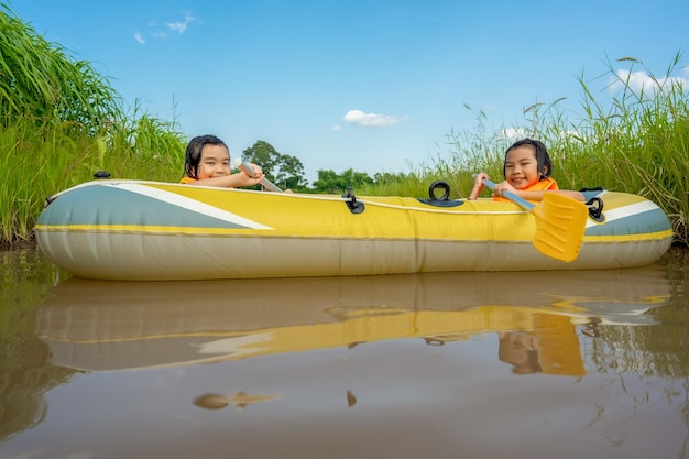 Kinder spielen und Ruderboot im Fluss des Bio-Bauernhofs auf dem Land