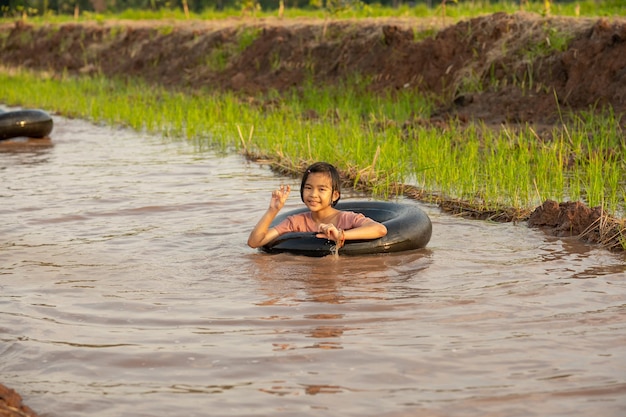 Kinder spielen und schwimmen im Kanal des Bio-Bauernhofs auf dem Land