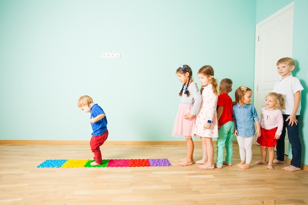 Kinder stehen barfuß in einer Reihe zwischen taktilen Kunststoff-Massagematten