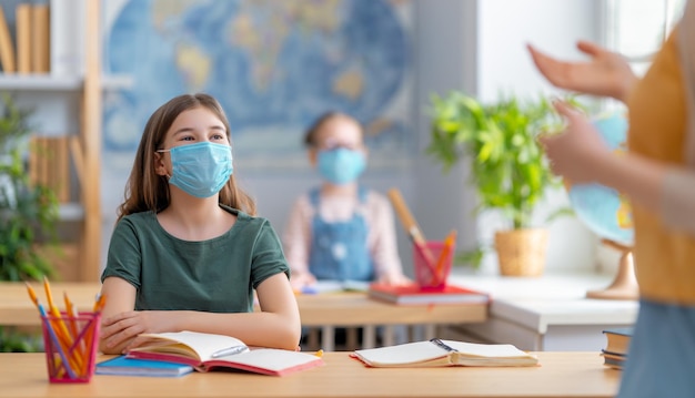 Kinder tragen Gesichtsmasken, die im Unterricht lernen