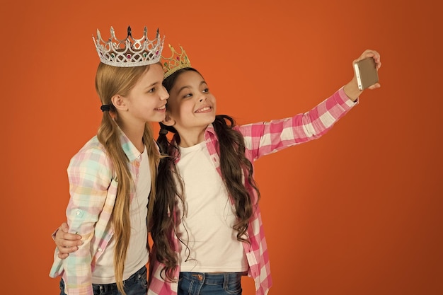 Kinder tragen goldene Kronen Symbol Prinzessin Warnzeichen eines verwöhnten Kindes Vermeiden Sie es, verwöhnte Kinder zu erziehen Mädchen, die ein Selfie-Foto mit einer Smartphone-Kamera machen Konzept für verwöhnte Kinder Fordern Sie mehr Aufmerksamkeit