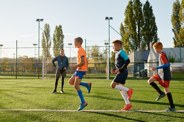 Kinder üben Fußball auf dem Rasenplatz unter der Kontrolle des Fußballtrainers. Gruppe von Jungen, die im Stadion trainieren