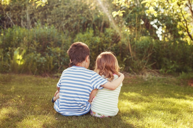 Kinder umarmen sich im Garten beim Sonnenuntergang Bruder mit seiner kleinen Schwester im Freien