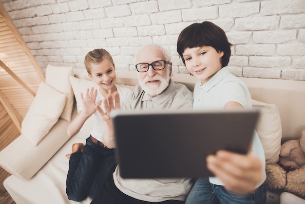 Kinder und Großvater machen Videoanruf mit Tablet.