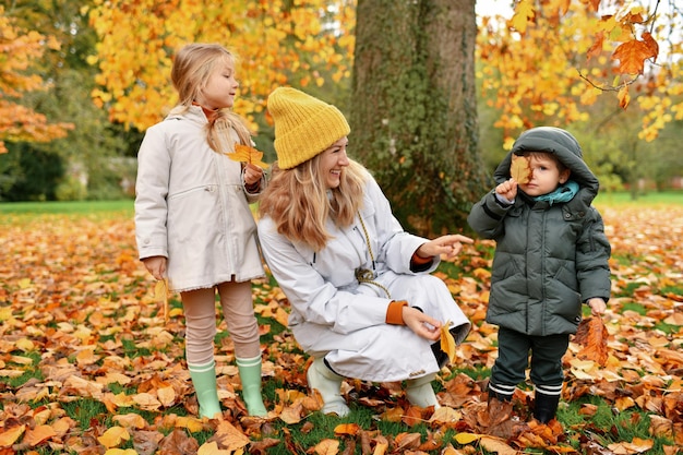 Kinder und Mutter spielen im Herbstpark