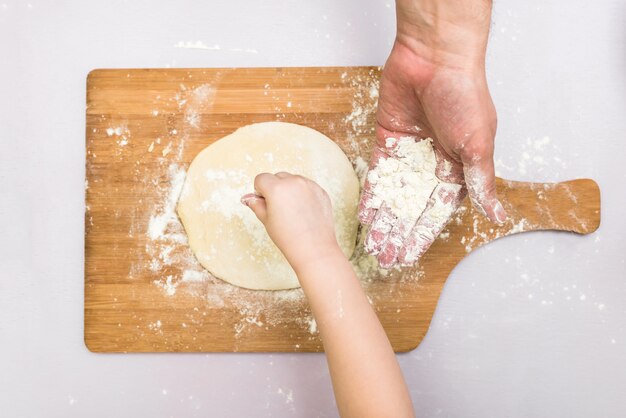 Kinder- und Vatihände rollten Teig