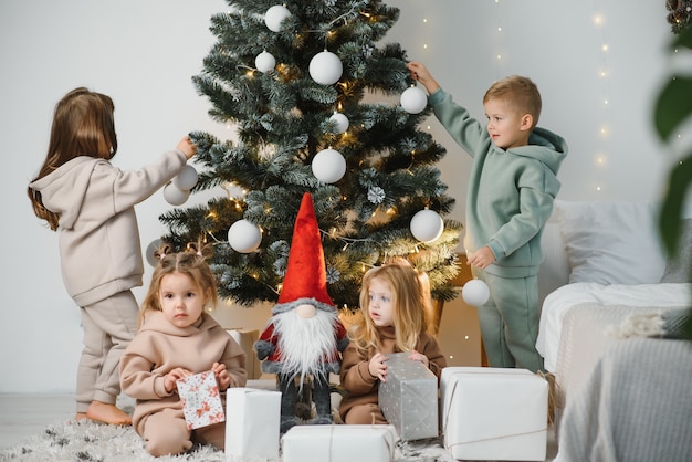 Kinder unter dem Weihnachtsbaum mit Geschenken und Spielzeug