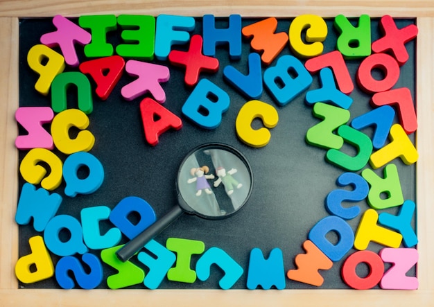 Kinder unter Lupe und bunte Buchstaben des Alphabets