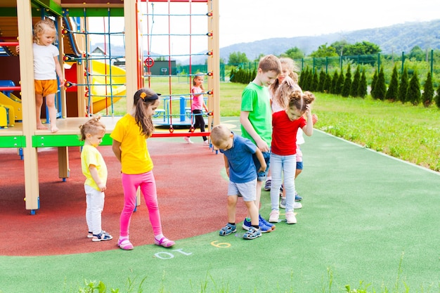 Kinder unterschiedlichen Alters springen vor Freude auf der weichen Decke auf dem Spielplatz im Freien