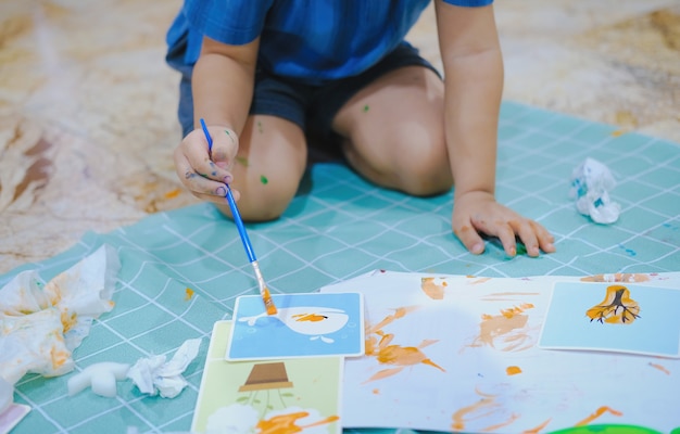 Foto kinder verwenden pinsel, um aquarelle auf papier zu malen, um ihre fantasie zu fördern und ihre lernfähigkeiten zu verbessern.