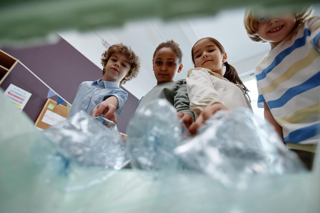 Kinder werfen Plastikflaschen in den Papierkorb, pov