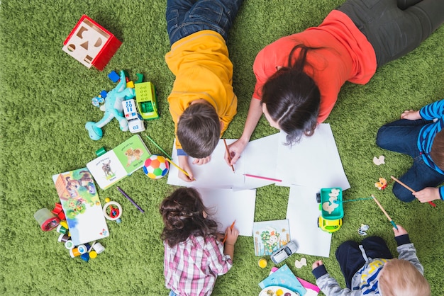 Kinder zeichnen und spielen auf Teppich