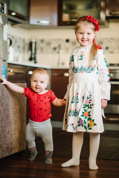 Kinder zu Hause Porträt eines netten Mädchens, das in ukrainischem, volkstümlich besticktem Kleid gekleidet ist, das für ein Foto posiert Kind mit Kranz aus Mohnblumen auf dem Kopf Nationales ethnisches traditionelles Kostüm oder Kleid