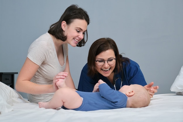 Kinderärztin in blauer Uniform mit Stethoskop im Gespräch mit der jungen Mutter des kleinen Jungen