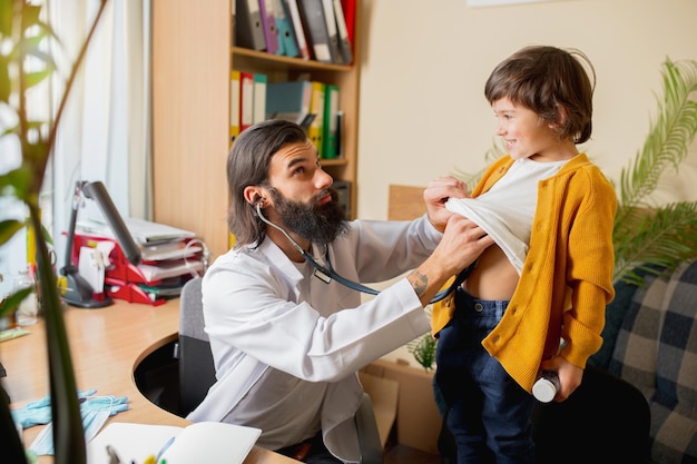 Kinderarzt, der ein Kind in einer komfortablen Arztpraxis untersucht