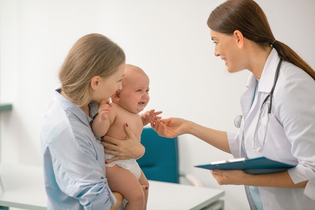 Kinderarzt. Junge Mutter besucht Kinderarzt mit ihrem kleinen Baby