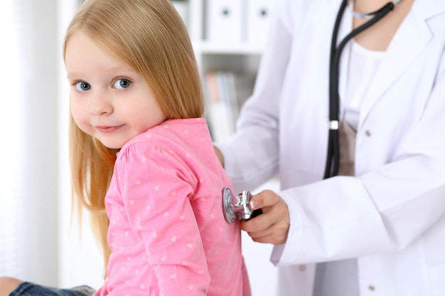 Foto kinderarzt kümmert sich um baby im krankenhaus kleines mädchen wird vom arzt mit stethoskop untersucht krankenversicherung und hilfskonzept