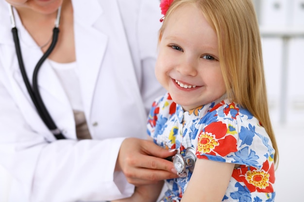 Foto kinderarzt kümmert sich um baby im krankenhaus kleines mädchen wird vom arzt mit stethoskop untersucht krankenversicherung und hilfskonzept