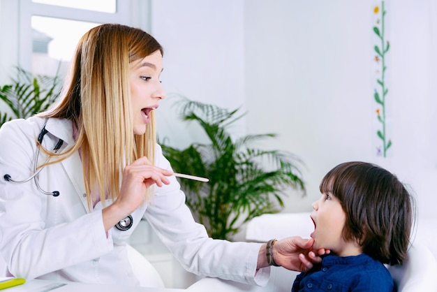 Kinderarzt untersucht den Hals des kleinen Jungen