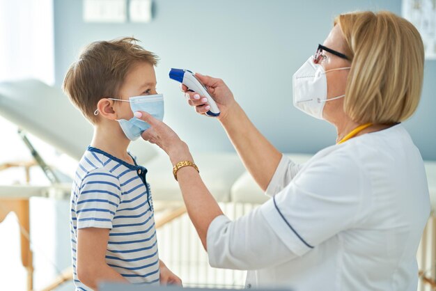 Kinderarzt untersucht kleine Kinder bei der Temperaturkontrolle in der Klinik. Foto in hoher Qualität