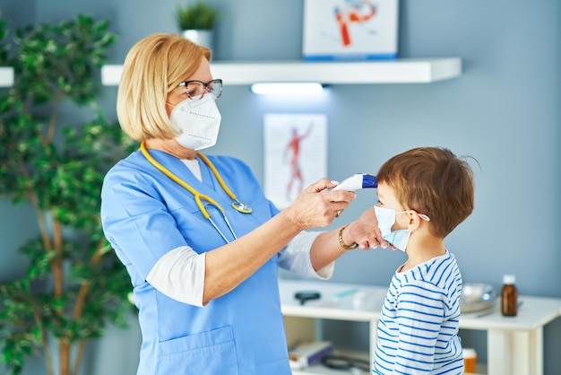 Kinderarzt untersucht kleine Kinder bei der Temperaturkontrolle in der Klinik. Foto in hoher Qualität