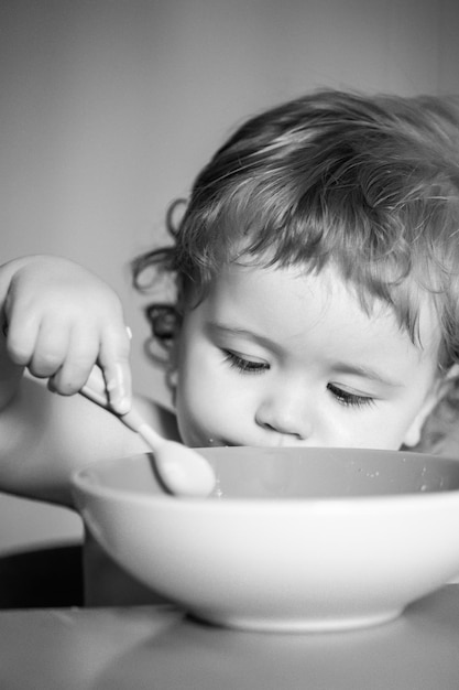 Kinderbaby isst Suppe in der Küche mit Geschirr und Löffel